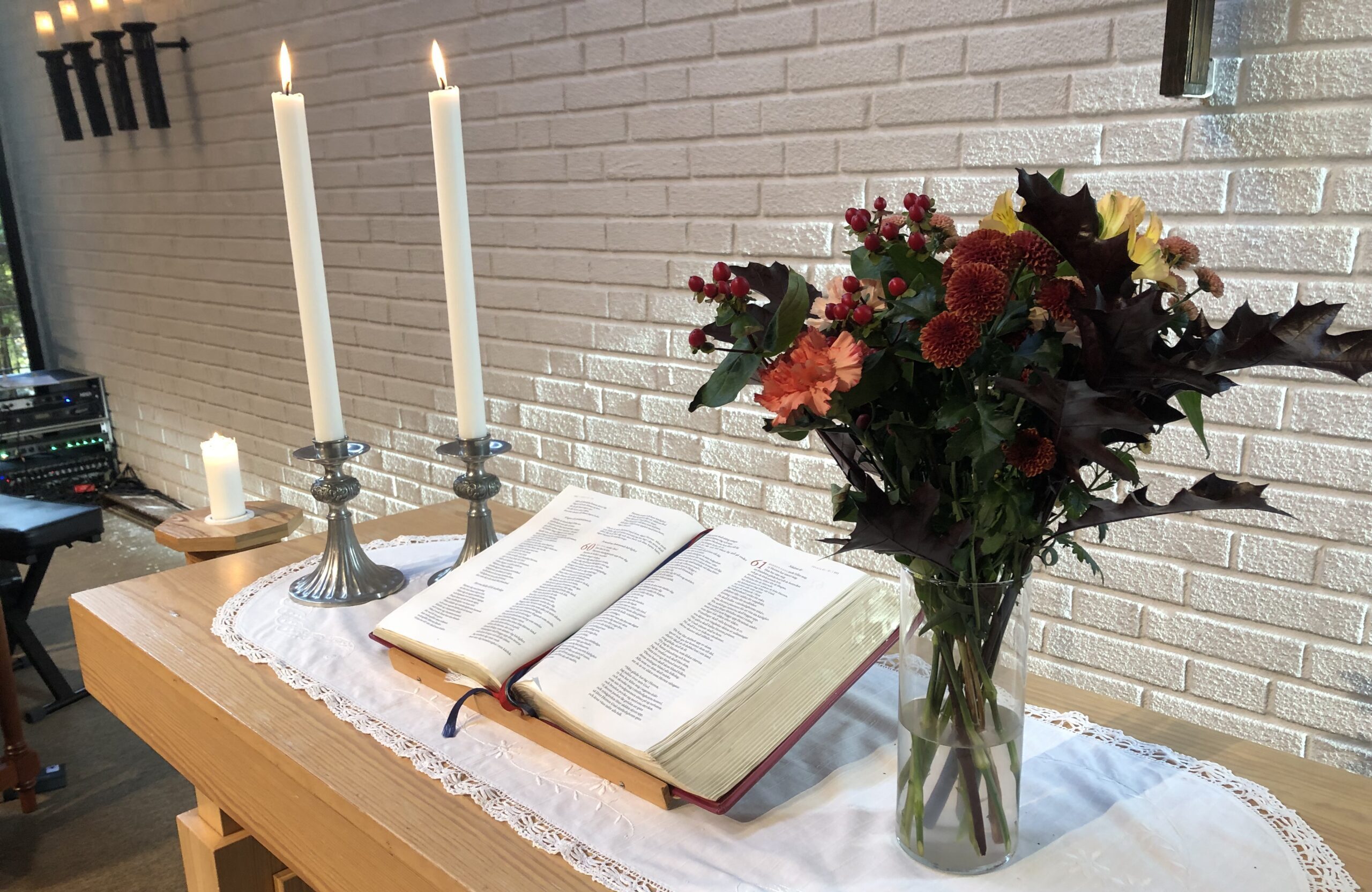 Ett altare med en uppslagen bibel, två levande ljus och en blombukett